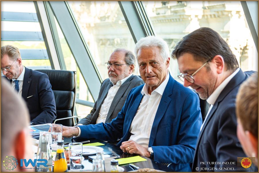 Drei Gesprächspartner an einem Konferenztisch, einander zugewandt und im Austausch.