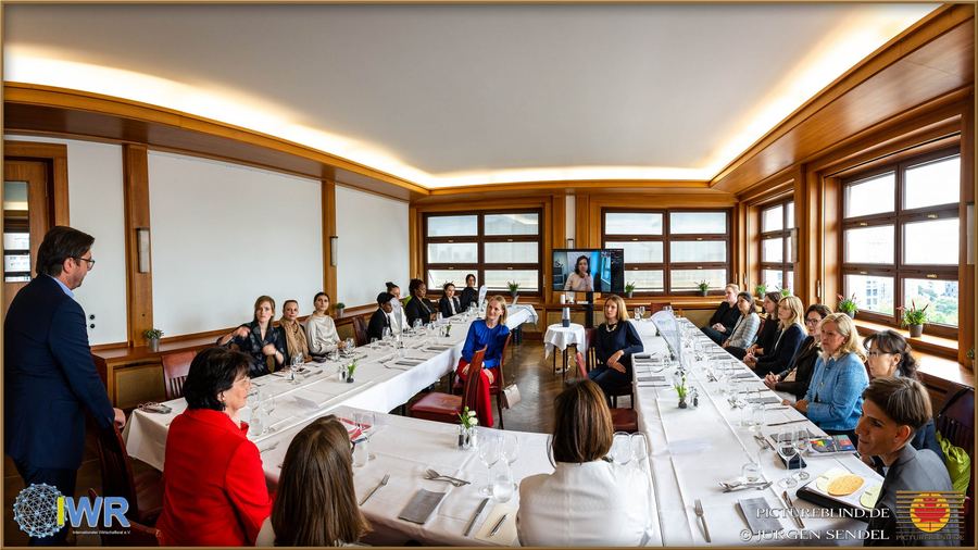 Langer, festlich eingedeckter Konferenztisch in einem hellen Saal, an dem Teilnehmerinnen und Teilnehmer einer Veranstaltung sitzen.